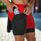 The image shows a close-up of a man wearing red 2-in-1 gym sports shorts with a black inner compression layer. The inner layer features a side pocket where the man is placing a smartphone. The red outer shorts have a drawstring waistband for an adjustable fit, and the black compression shorts underneath offer support and practicality during workouts. The outdoor background, with a blurred street scene, suggests that these shorts are versatile for both athletic and casual use, combining style and functionali