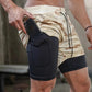 Man wearing beige camo 2-in-1 gym shorts, placing a phone in the side pocket of the black inner compression layer.