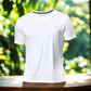 White polyester running T-shirt with 'RUN' text, displayed in a natural outdoor setting with vibrant green foliage in the background.