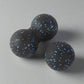 Black massage balls with blue speckles, featuring a double and single ball design for deep tissue muscle relief, displayed on a light grey background.