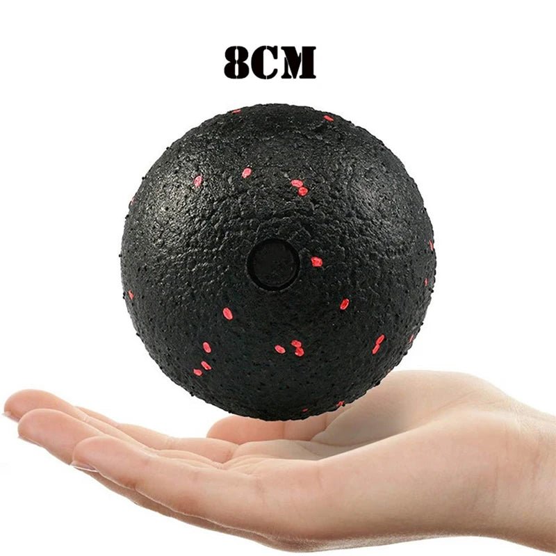 Hand holding an 8cm black massage ball with red speckles, designed for effective muscle tension relief and easy portability.