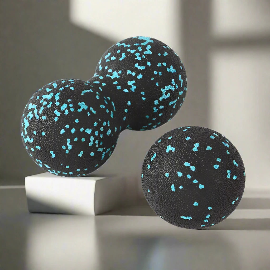 Black double massage ball and single ball with blue speckles, displayed on a neutral surface, ideal for muscle relaxation and deep tissue therapy.