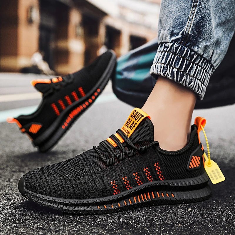 Black and orange lightweight men's running shoes with a breathable mesh upper and slip-resistant sole, shown in use by a person on a street, highlighting comfort and style.