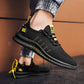 Close-up side view of a person wearing black and yellow lightweight men's running shoes with a breathable mesh upper and slip-resistant outsole, showcasing the shoe's flexibility and comfort.